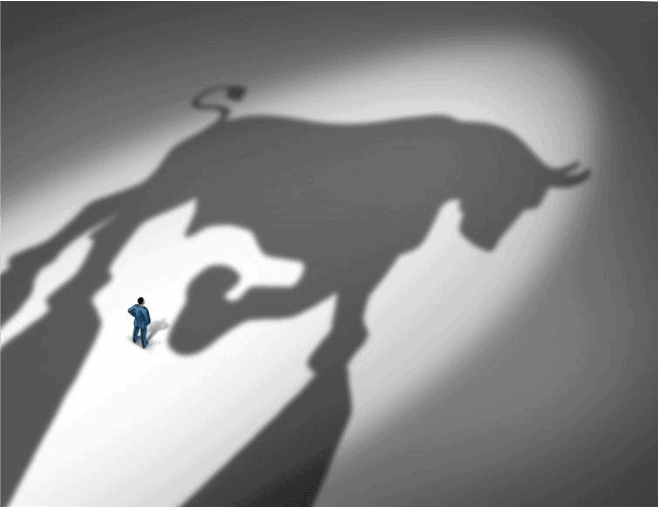 Businessman standing in front of giant bull shadow